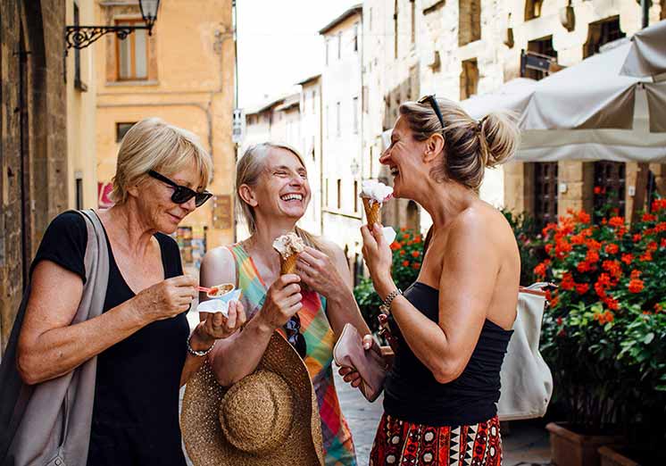 Image show three woman in street standing and eating icecream