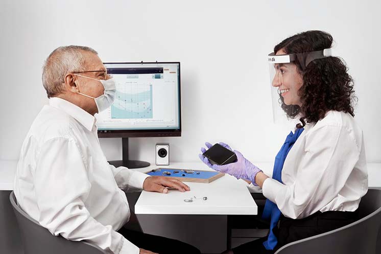 Image show an audiologist showing hearing instruments to a customer