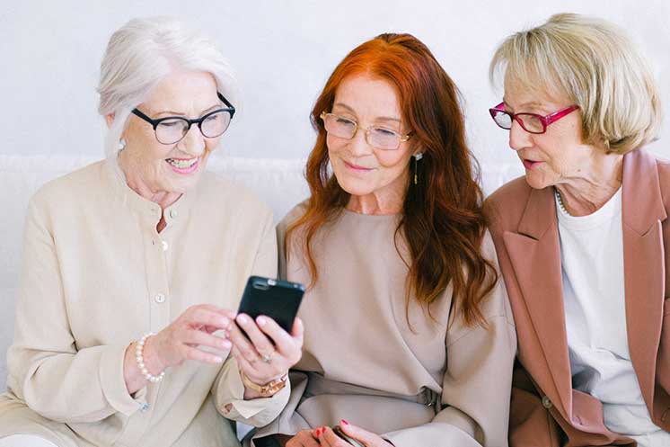 Image show three woman looking at a phone