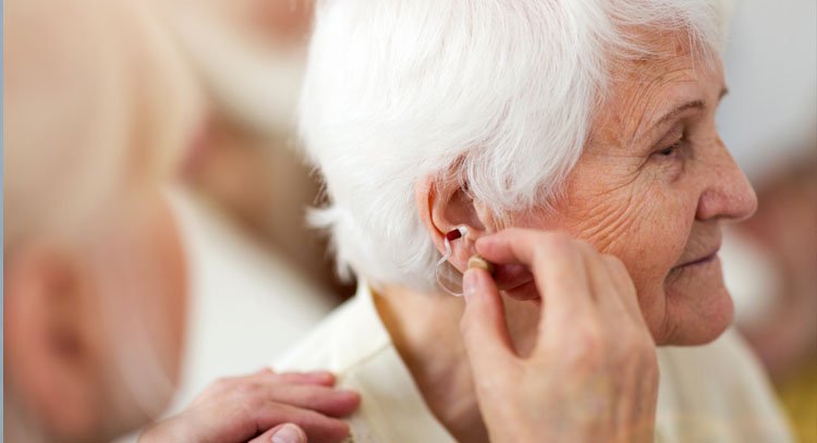 old woman adjusting hearing aid