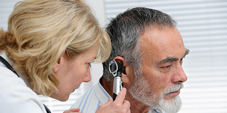 Image show audiologist look into an ear