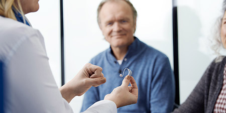 Image show audiologist show a hearing aid to customers