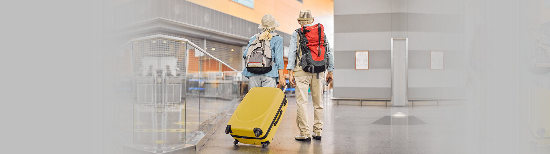 two older people with backpacks at the airport