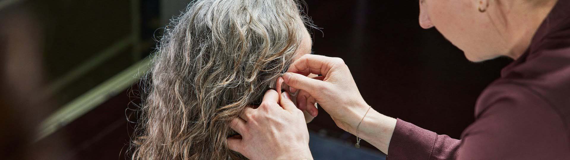 person helping someone put hearing aids on