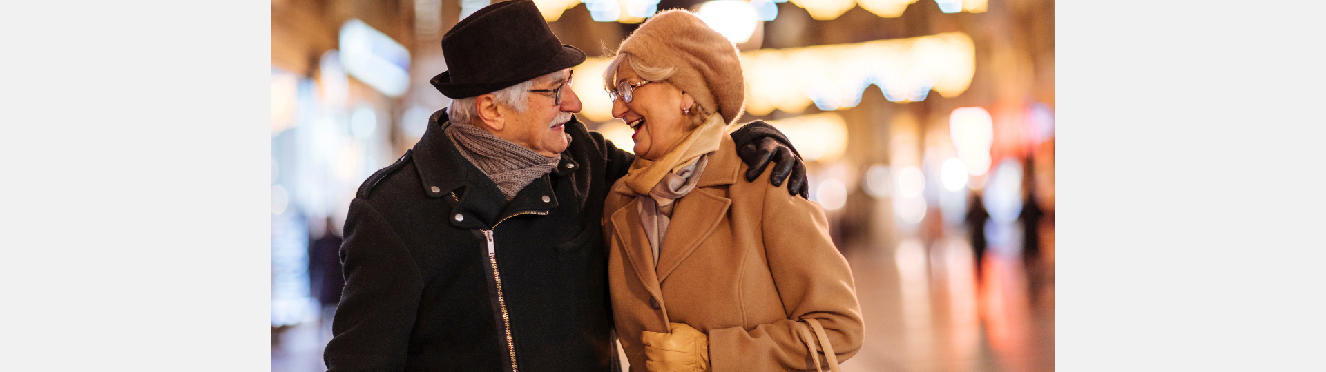 a man and woman hugging. they are wearing winter coats and are outside at night.