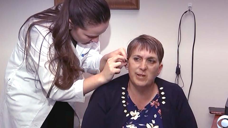 a woman has a hearing aid put in her ear