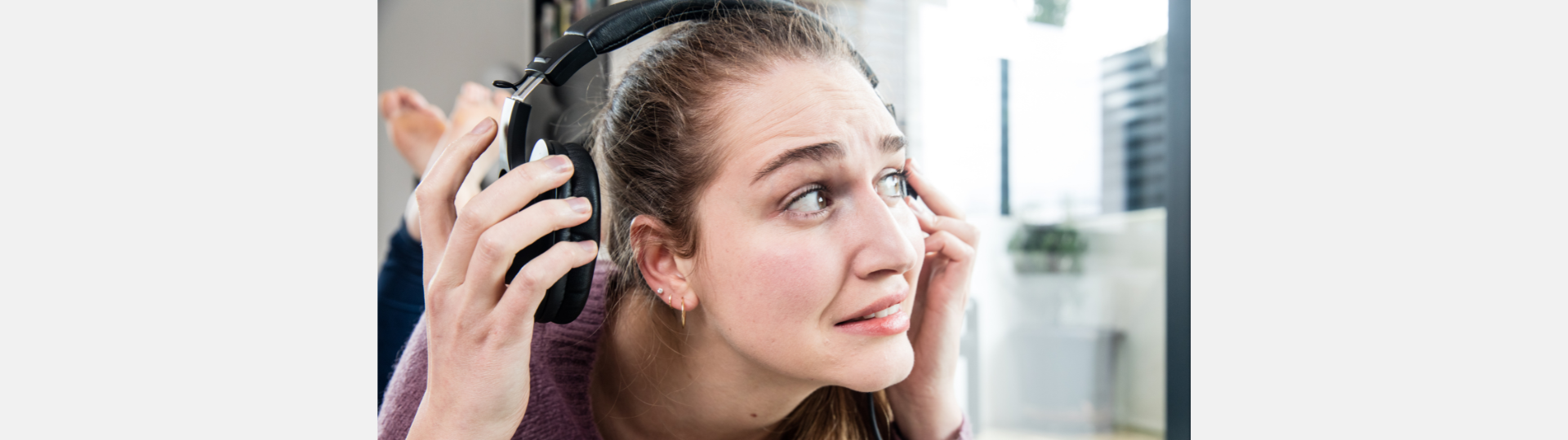 woman wearing headphones who looks like she is in pain