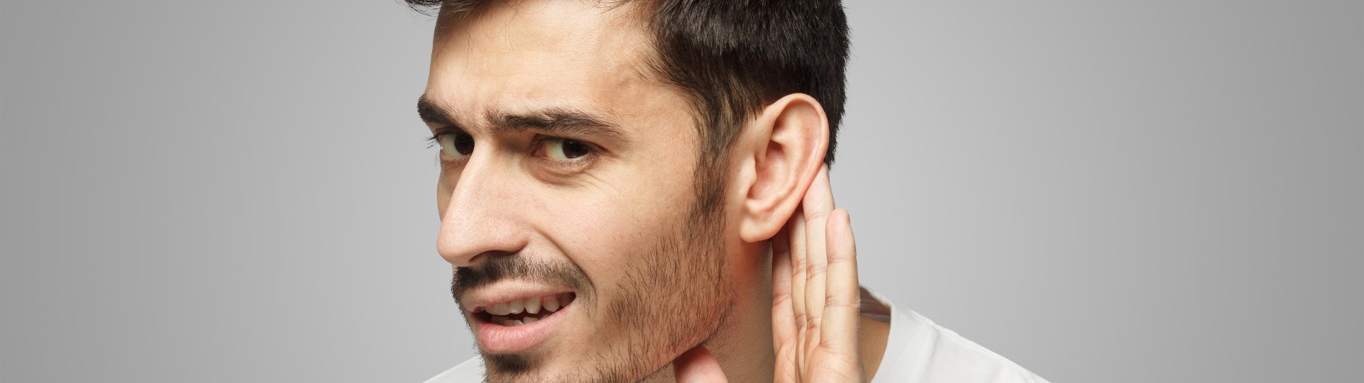 a masculine person holding his hand up to his ear because he has suddenly lost his hearing