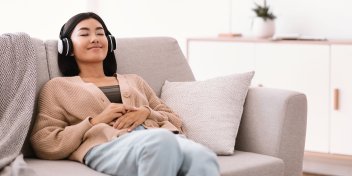 woman wearing headphones for sound therapy on her couch