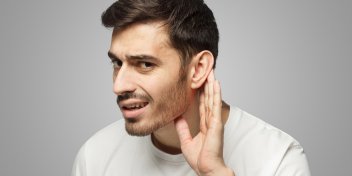 a masculine person holding his hand up to his ear because he has suddenly lost his hearing