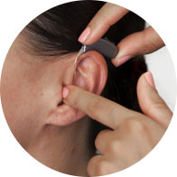 Hearing care provider fitting hearing aid on an ear