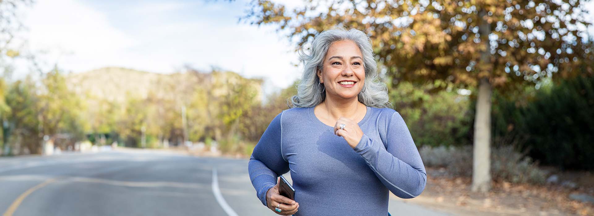 Woman smiling and jogging on a crisp fall day