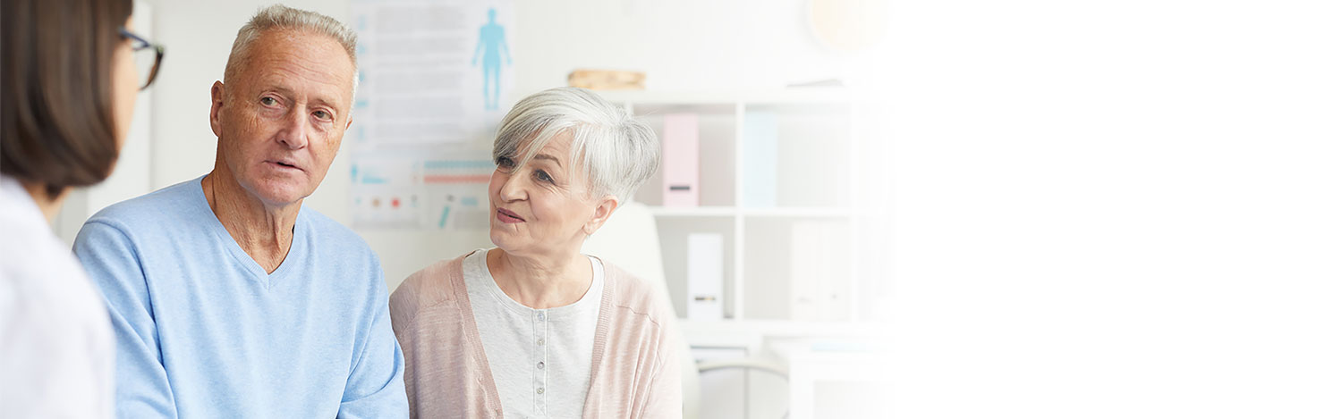 Image show man and woman looking at a HearingLife audiologist