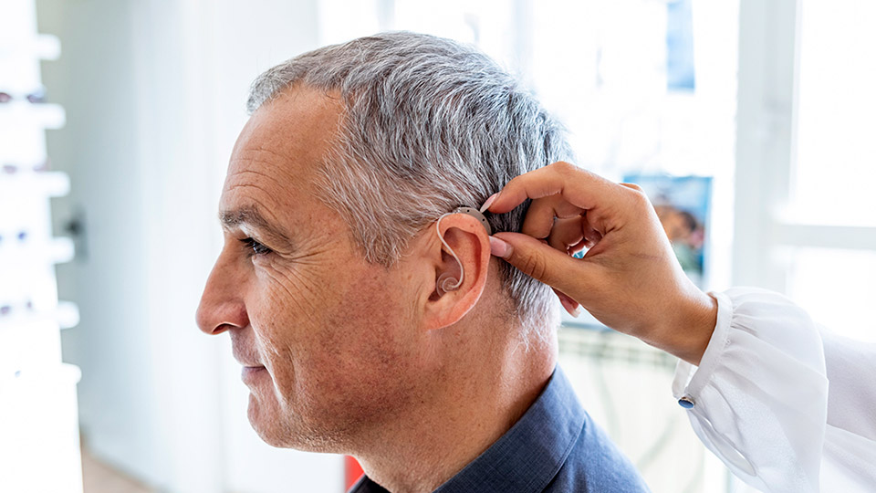 Image show man get fitted with a hearing aid