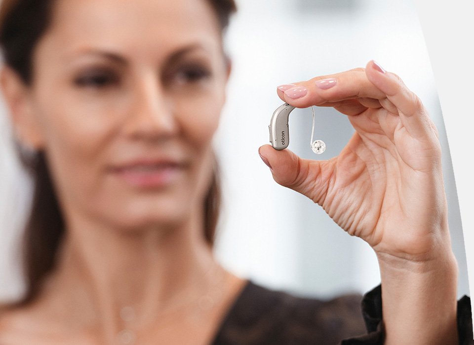 Woman holding an Oticon Real™ hearing aid