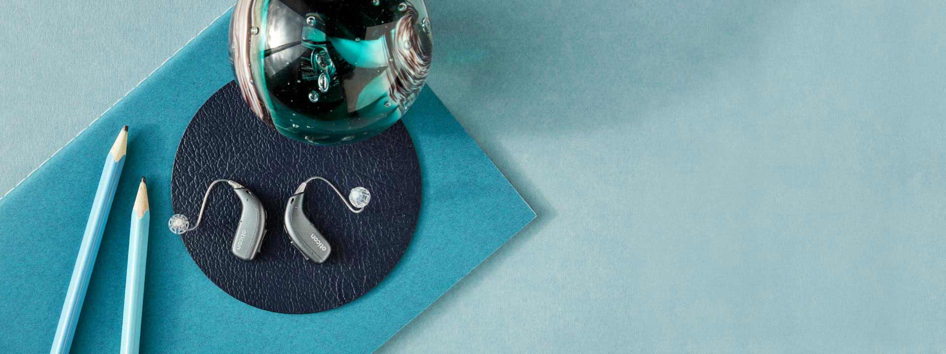 Image shows two hearing aids placed on a blue background