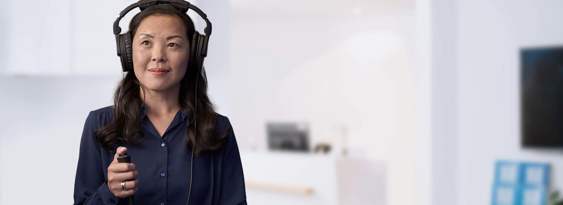 Image shows woman with headphone taking the online hearing test