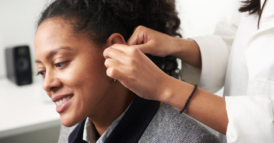 Image show woman get fitted with a hearing aid