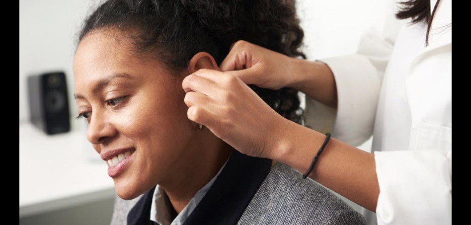 Image shows woman having her hearing aids repair/ adjustment