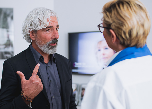 Image shows man talking to audiologist in clinic