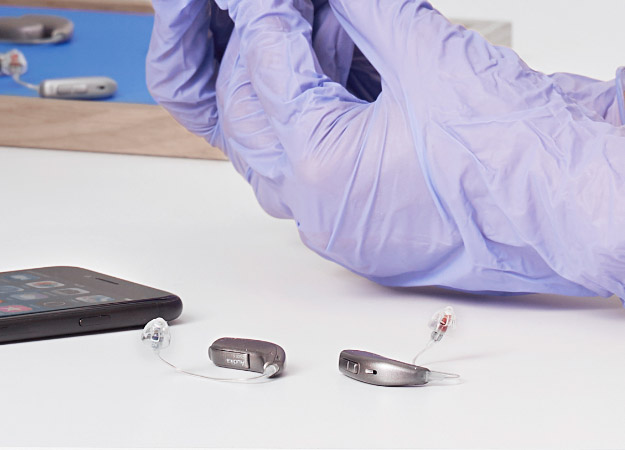 Image shows hearing aids on the table next to mobile phone
